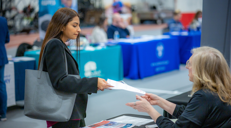 Female student handing her resume to an employer at a job fair